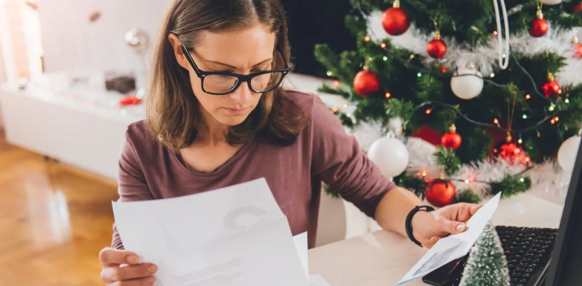 Eine Frau sitzt am Schreibtisch und fragt sich "wie wird Weihnachtsgeld versteuert"