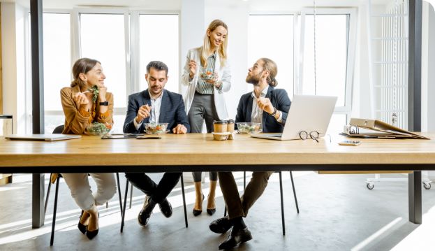 Gruppe von Kollegen macht Mittagspause & spricht über Ziele im Employer Branding