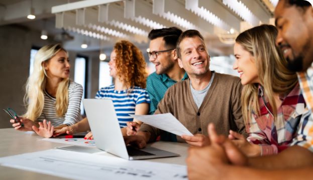 Gamification Beispiele Mobil Fröhliche Gruppe Mitarbeiter am Schreibtisch