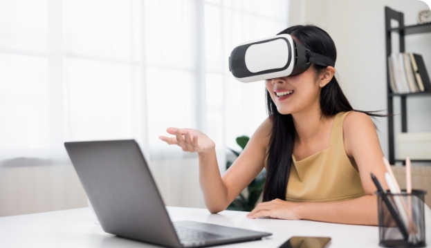 Frau mit VR-Brille sitzt vor Laptop