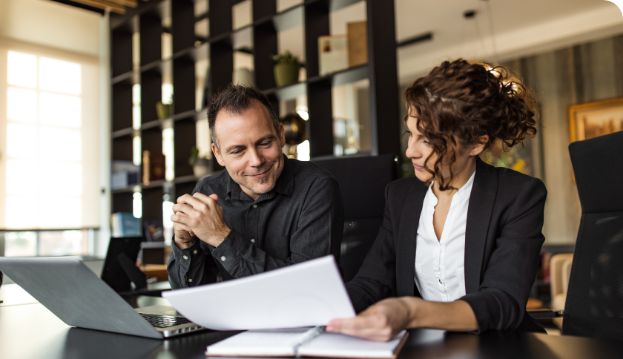 Zwei Businessleute diskutieren über einen Lebenslauf gebeugt.